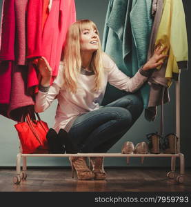 Woman choosing clothes to wear in mall or wardrobe. Happy smiling pretty woman choosing clothes to wear in wardrobe. Gorgeous young girl customer shopping in mall shop. Fashion clothing sale concept.