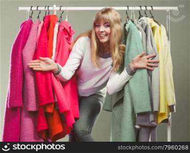 Woman choosing clothes to wear in mall or wardrobe. Happy smiling pretty woman choosing clothes to wear in wardrobe. Gorgeous young girl customer shopping in mall shop. Fashion clothing sale concept.