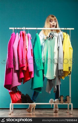 Woman choosing clothes to wear in mall or wardrobe. Surprised pretty woman choosing clothes to wear in wardrobe. Attractive young girl customer shopping in mall shop. Fashion clothing sale concept.