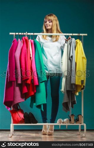 Woman choosing clothes to wear in mall or wardrobe. Pretty woman choosing clothes to wear in wardrobe. Attractive young girl customer shopping in mall shop. Fashion clothing sale concept.