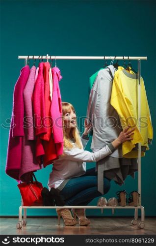 Woman choosing clothes to wear in mall or wardrobe. Happy smiling pretty woman choosing clothes to wear in wardrobe. Gorgeous young girl customer shopping in mall shop. Fashion clothing sale concept.
