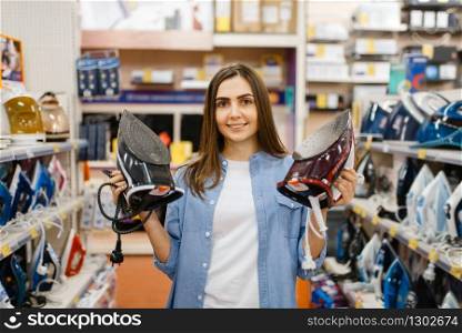 Woman choosing electric iron in electronics store. Female person buying home electrical appliances in market. Woman choosing electric iron in electronics store