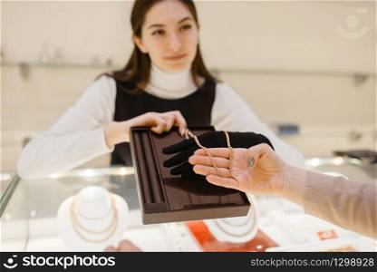 Woman choosing golden chain in jewelry store. Female person buying gold decoration in jewellery shop. Woman choosing golden chain in jewelry store
