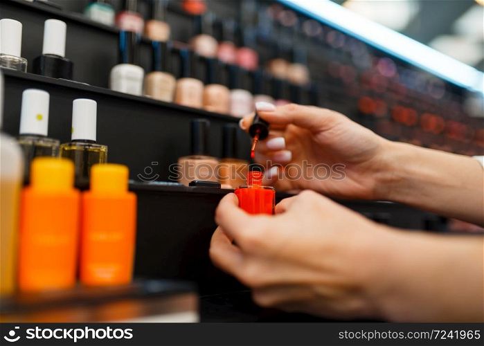 Woman choosing nail varnish color in cosmetics store. Buyer in luxury beauty shop salon, female customer in fashion market. Woman choosing nail varnish in cosmetics store
