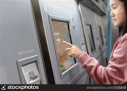 Woman choosing the destination on subway train ticket machine. Transportation concept