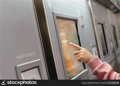 Woman choosing the destination on subway train ticket machine. Transportation concept