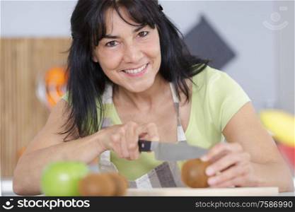 woman chopping a tomato on a chopping board