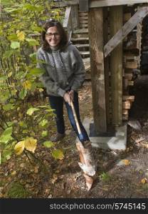 Woman chopping firewood with axe, Lake of The Woods, Ontario, Canada