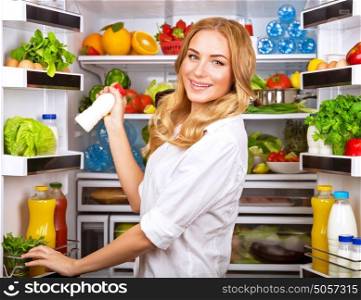 Woman chosen milk in opened refrigerator, cool new friedge full of tasty organic nutrition, female preparing to cook, healthy eating concept