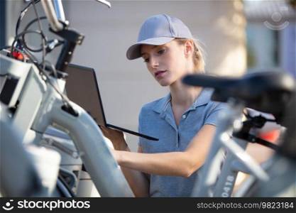 woman city worker checking rent bike station on laptop