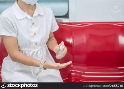 woman clean hand by alcohol spray sanitizer in train or public transportation, protection Coronavirus disease infection. Personal hygiene, safety and travel transport under COVID-19 concepts