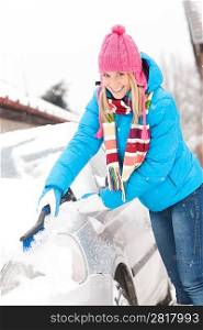 Woman cleaning car hood of snow brush happy winter wiping