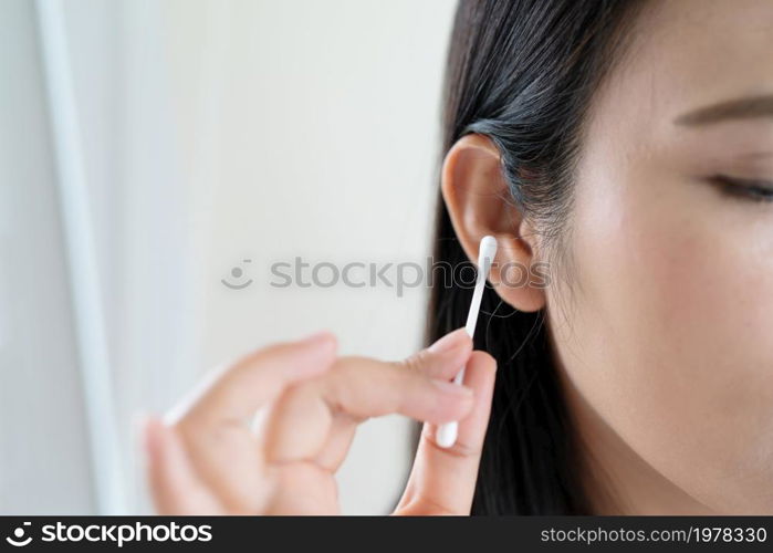 woman cleaning ear with cotton swab. Healthcare and ear cleaning concept