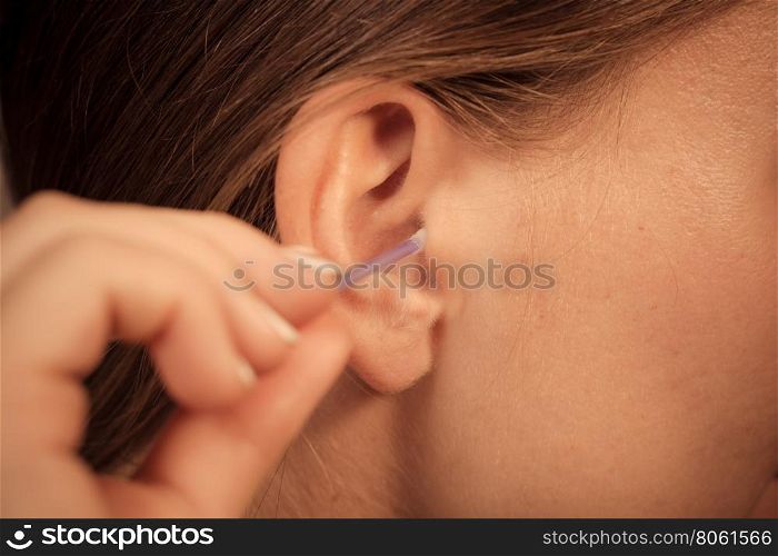 Woman cleaning ear with cotton swabs closeup . Hygiene concept. Woman cleaning ear with cotton swabs closeup