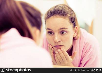 Woman cleaning peeling her face in bathroom, making facial massage with scrub. Girl taking care of skin condition. Hygiene. Skincare spa treatment. . Woman cleaning her face with scrub in bathroom.