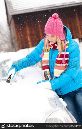 Woman cleaning snow car hood with scraper winter wiping young
