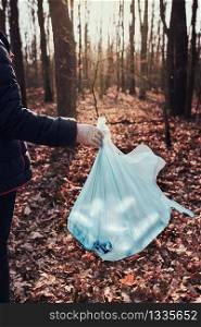 Woman cleaning up a forest. Volunteers picking plastic waste to bags. Concept of plastic pollution and too many plastic waste. Environmental issue. Environmental damage. Responsibilitiy for environment. Real people, authentic situations