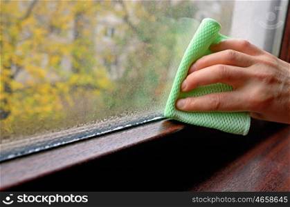 Woman cleaning water condensation on window