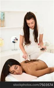 Woman cleans skin of the body with coffee scrub in spa wellness center. Beauty and Aesthetic concepts.. Woman cleans skin of the body with coffee scrub in spa wellness center.