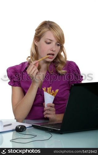 Woman clerk eating French fries at her desk