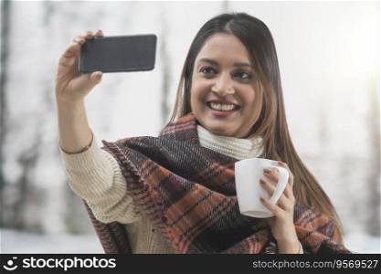 Woman clicking a selfie on her phone with a coffee mug in her hand 