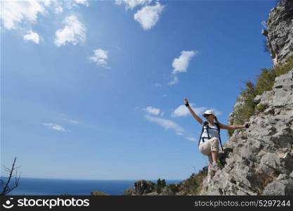woman climbs mountainside to top