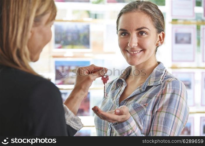 Woman Collecting Keys To Property From Estate Agent