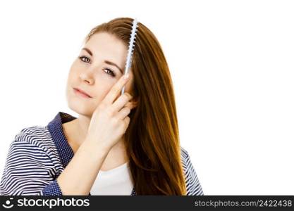 Woman combing her healthy hair using comb. Young latin female with beautiful natural brown straight long hairs, studio shot isolated on white. Woman brushing her long hair using comb
