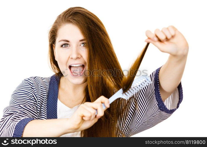 Woman combing her healthy hair using comb. Young latin female with beautiful natural brown straight long hairs, studio shot isolated on white. Woman brushing her long hair using comb