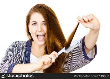Woman combing her healthy hair using comb. Young latin female with beautiful natural brown straight long hairs, studio shot isolated on white. Woman brushing her long hair using comb