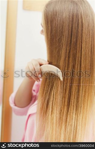 Woman combing her long hair in bathroom . Woman combing brushing her long smooth hair in bathroom. Girl taking care refreshing her hairstyle. Haircare concept. Filtered image
