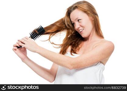 Woman combing tangled red hair after shower on white background