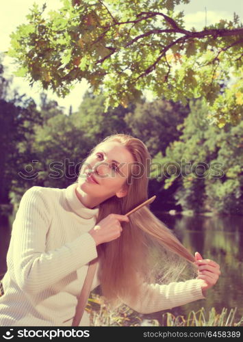 woman combs long hair on the river bank,with a retro effect