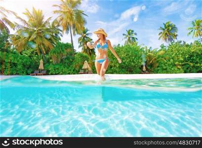 Woman comes into water on the beach, beautiful tropical island, luxury summertime vacation, happiness and freedom concept