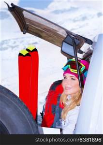 Woman comes on ski resort, sitting on the car with all sports equipment, enjoying winter holidays, active vacation concept