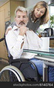 Woman Comforting Depressed Man In Wheelchair At Home