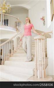 Woman coming down staircase in luxurious home smiling