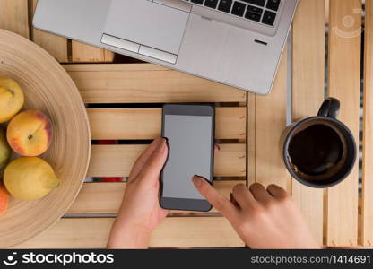 woman computer smartphone drink mug office supplies technological devices. Young lady using and holding a dark smartphone in a crate table with a mug of black coffee. Office supplies, cell phone, technological devices and wooden desk.