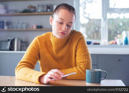 Woman Concerned About Excessive Use Of Social Media Laying Mobile Phone Down On Table