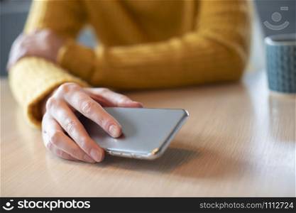 Woman Concerned About Excessive Use Of Social Media Laying Mobile Phone Down On Table
