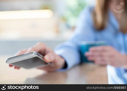 Woman Concerned About Excessive Use Of Social Media Laying Mobile Phone Down On Table