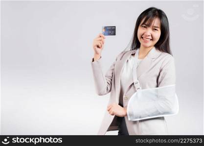 Woman confident smile broken arm after accident and wear arm splint for treatment she emergency pay medical bills by credit card, Happy Asian female sling support hand isolated on white background