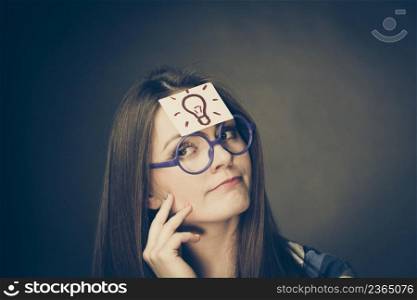 Woman confused thinking seeks a solution, paper card with light idea bulb on her head. Student girl looking for new ideas. Eureka creativity concept. Woman thinking seeks a solution