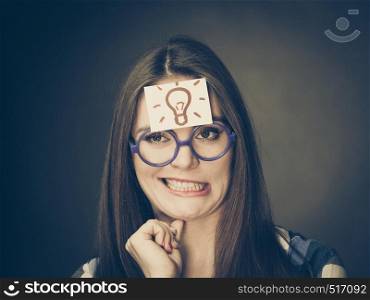 Woman confused thinking seeks a solution, paper card with light idea bulb on her head. Student girl looking for new ideas. Eureka creativity concept. Woman thinking seeks a solution