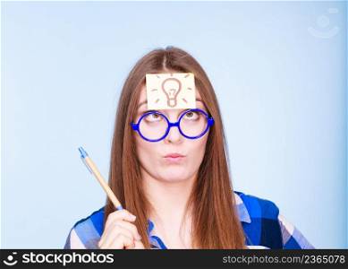 Woman confused thinking seeks solution, paper card with light idea bulb on her head. Girl is trying to create a new idea for some business project or case study studio shot on blue. woman thinking light idea bulb on head