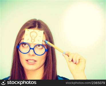 Woman confused thinking seeks solution, paper card with light idea bulb on her head. Girl is trying to create a new idea for some business project or case study studio shot on green. woman thinking light idea bulb on head