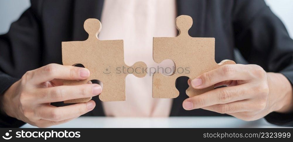 Woman connecting couple puzzle piece, wood jigsaw on table. Business solutions, mission, success, goals and strategy concepts