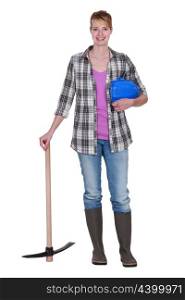 Woman construction worker standing with a pickaxe