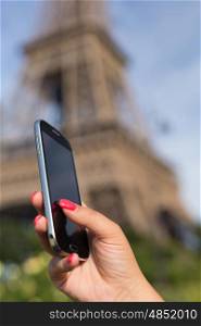Woman consulting her smartphone with Eiffel Tower on background