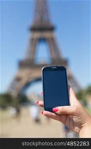 Woman consulting her smartphone with Eiffel Tower on background